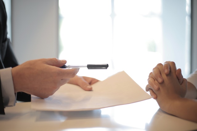 someone handing someone else a pen